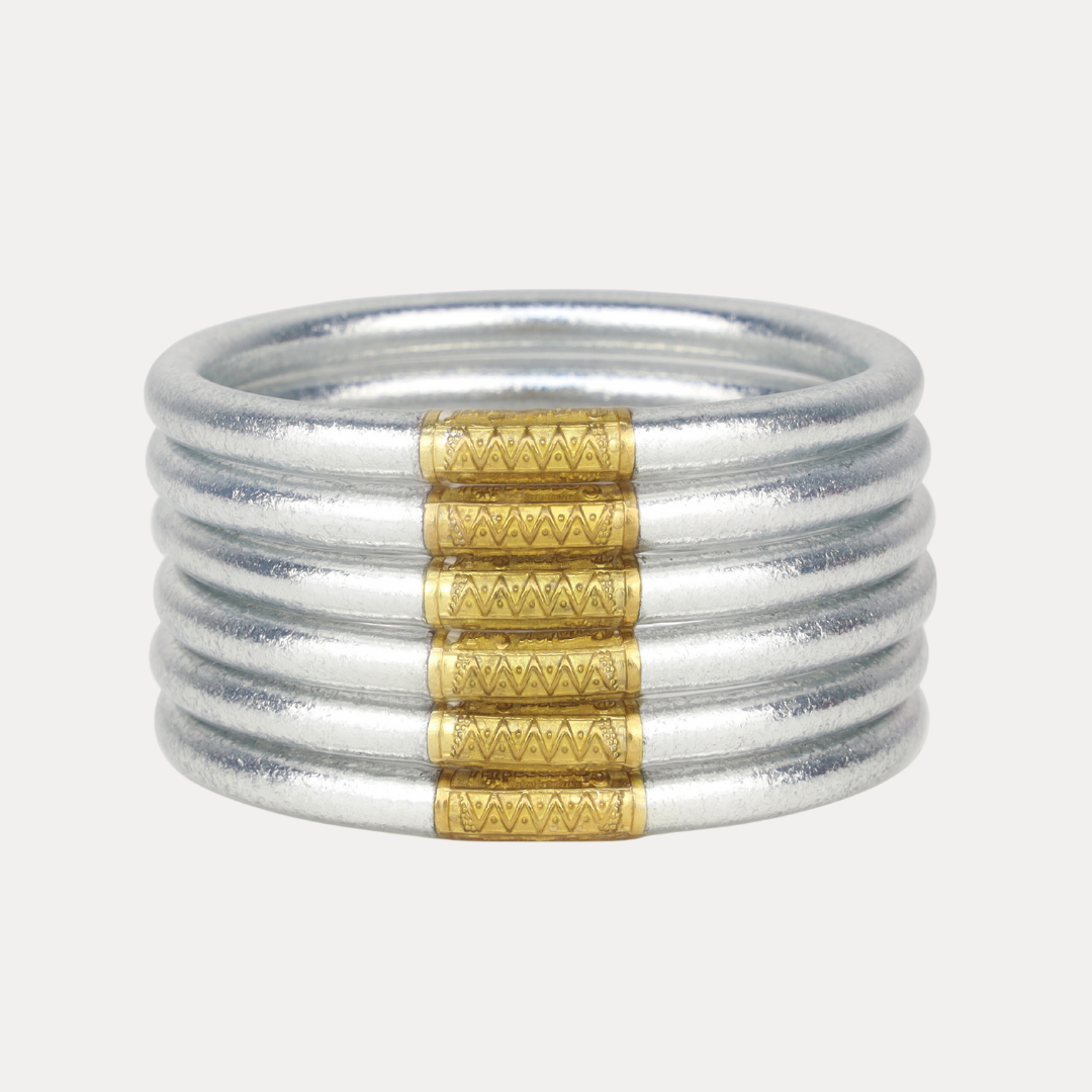 Set of silver bangles with gold accents on a white background